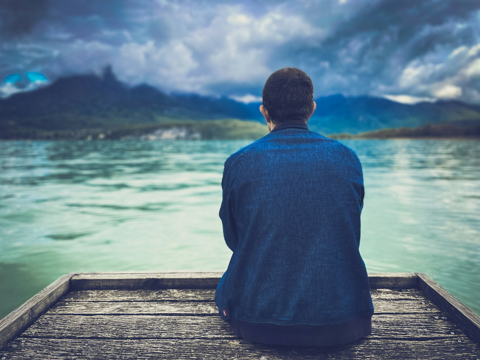 a man sitting on a dock looking at the water